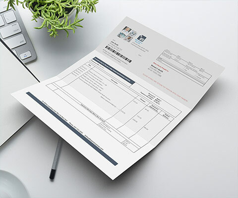 paper invoice sitting on a desk with a pen under it and plant and laptop to the left side