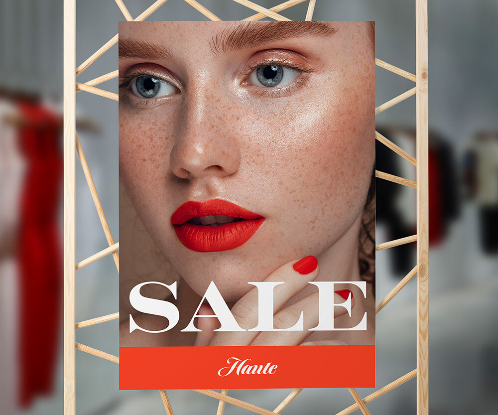 A sale sign that has a large image of a woman with blue eyes, freckles and red lipstick.